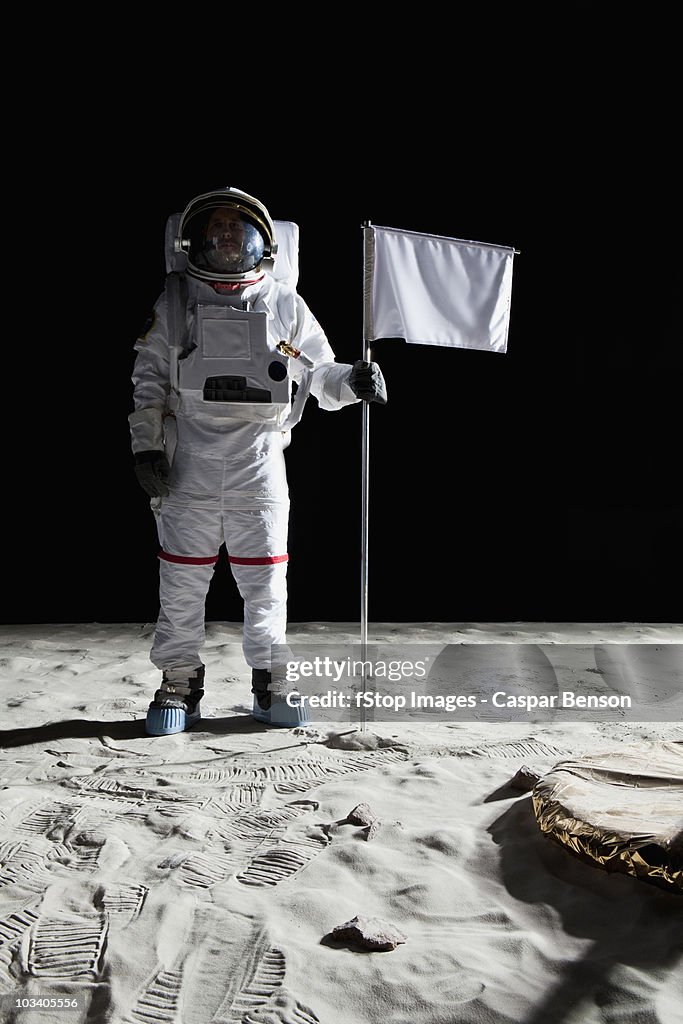 An astronaut standing next to a white flag