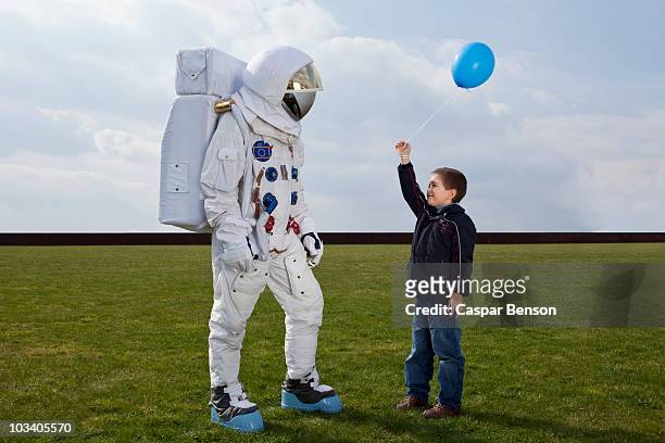 a boy holding out a balloon to an astronaut - respect kids stock pictures, royalty-free photos & images