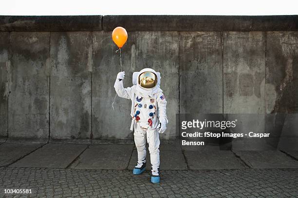an astronaut on a city sidewalk holding a balloon - freiheit stock-fotos und bilder