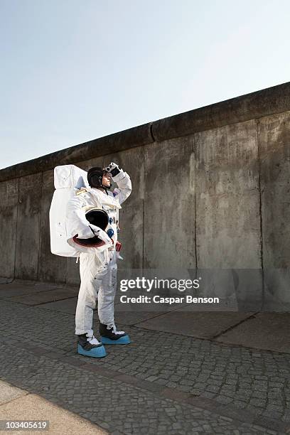 an astronaut on a city sidewalk looking up into the sky - astronaut helmet stock-fotos und bilder