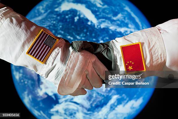 an american astronaut shaking hands with a chinese astronaut - astronaut hand stock pictures, royalty-free photos & images