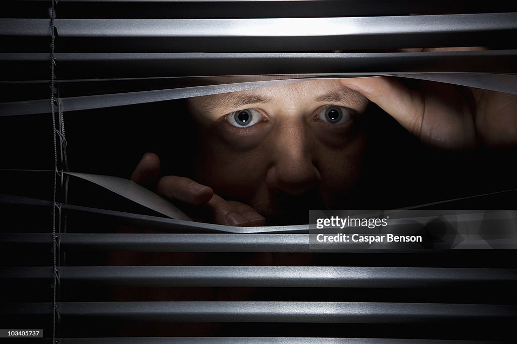 A man peeking through blinds
