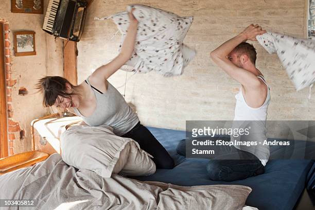 a boyfriend and his girlfriend having a pillow fight in bed - pillow fight fotografías e imágenes de stock