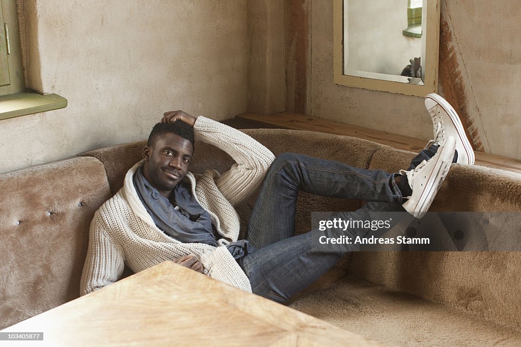 A stylish man reclining in a booth