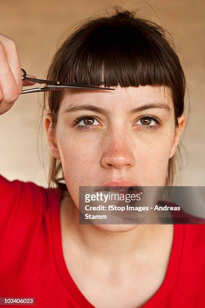 a woman trimming her own bangs - hairstyle stock-fotos und bilder