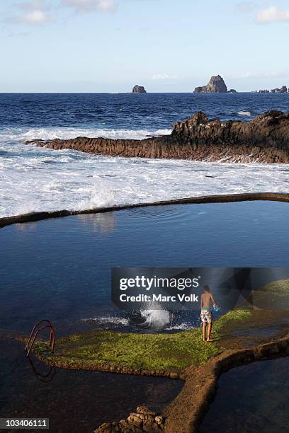 view of a boy standing by rock pools - el hierro stock pictures, royalty-free photos & images