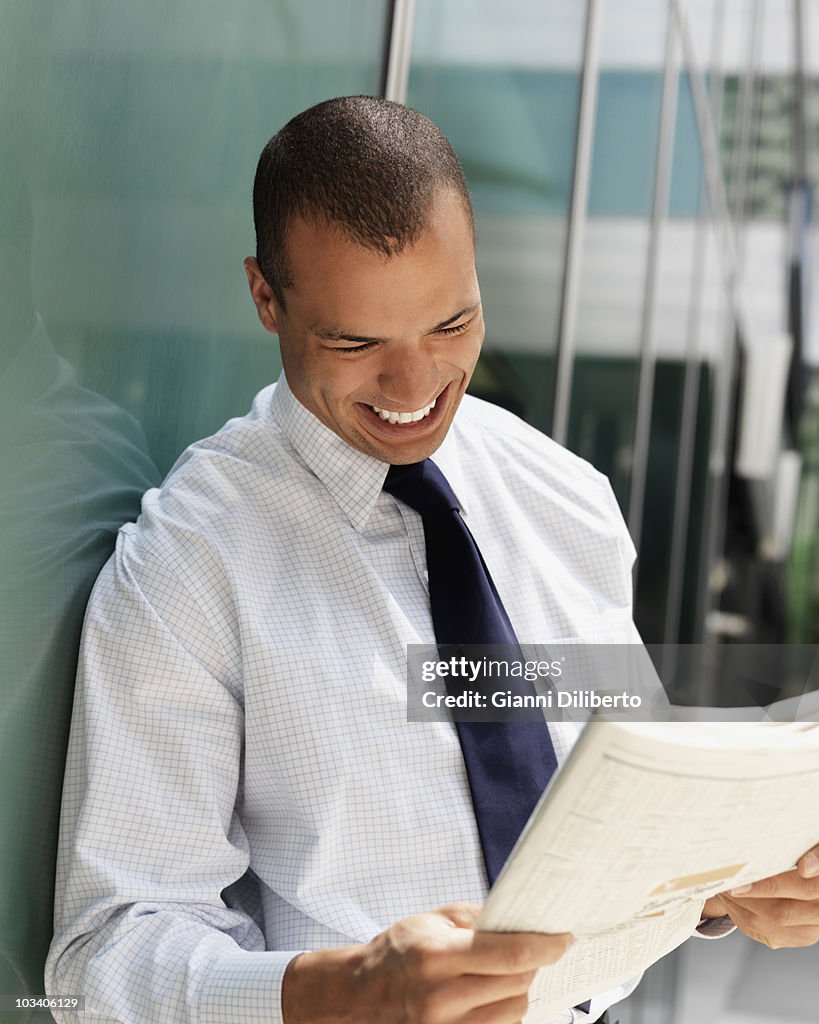 Smiling businessman reading a newspaper