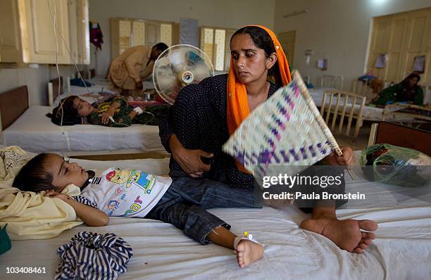 Pakistani mother fans her son who is suffering from diarrhea and a fever at a local clinic on August 16, 2010 in Charsadda , Pakistan. U.N....