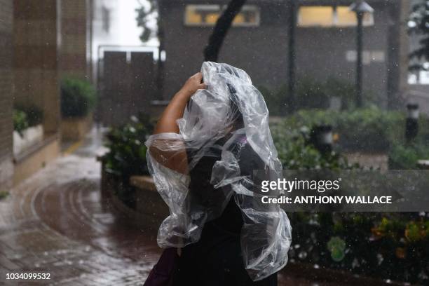 Pedestrian uses a plastic poncho during Super Typhoon Mangkhut in Hong Kong on September 16, 2018. - Typhoon Mangkhut rocked Hong Kong en route to...