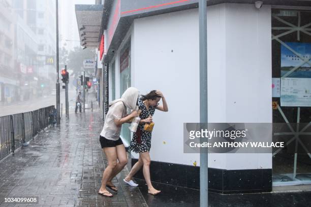 Residents walk through the rain during Super Typhoon Mangkhut in Hong Kong on September 16, 2018. - Typhoon Mangkhut rocked Hong Kong en route to...