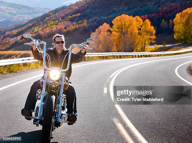 man riding motorcycle on windy road in autumn. - motorized vehicle riding stock pictures, royalty-free photos & images