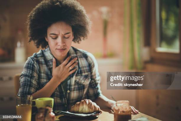 jonge african american vrouw gevoel misselijkheid tijdens ontbijt eetkamer. - offensive stockfoto's en -beelden