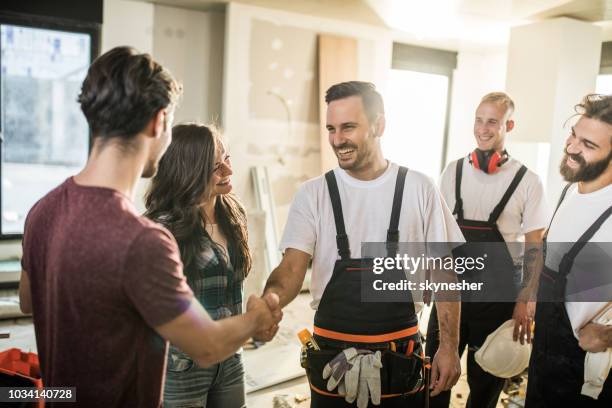 equipe de operários felizes acolher um casal para o apartamento deles. - classe trabalhadora - fotografias e filmes do acervo