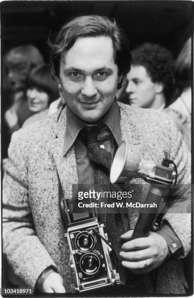 Portrait of American photographer Larry Fink, a camera in his hands, as he poses at an unspecified event, January 16, 1976.