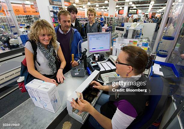 Employee Nina Steimel, right, rings up customers' puchases at a Saturn store, owned by Metro AG, in Munich, Germany, on Monday, Aug. 17, 2010. Retail...