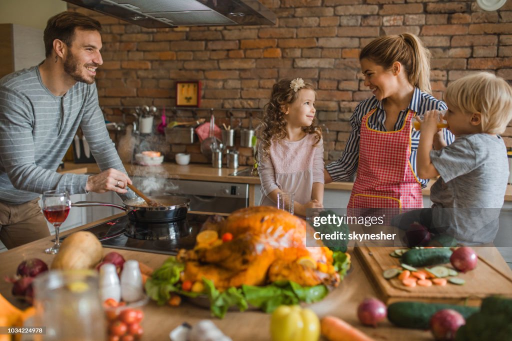 Young happy family enjoying while preparing meal for Thanksgiving in the kitchen.