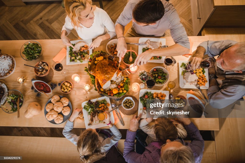 Above view of extended family talking at Thanksgiving dinner.