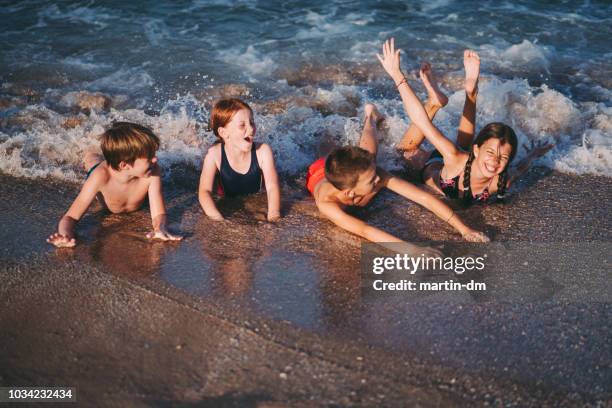 ビーチで横になっている 4 つの幸せな子供たち - barefoot redhead ストックフォトと画像
