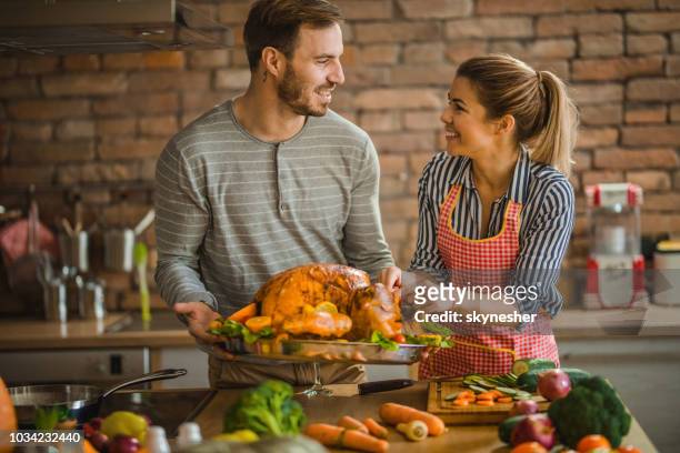 glückliches paar sprechen bei der verzierung der türkei am thanksgiving day. - chicken decoration stock-fotos und bilder
