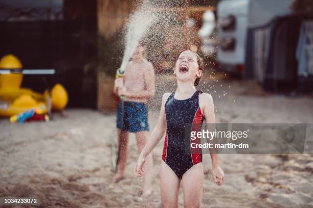 kids spatten van water met een tuinslang op het strand - cooling down stockfoto's en -beelden