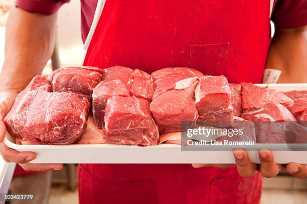 butcher holding fresh cut meat on tray - butcher foto e immagini stock