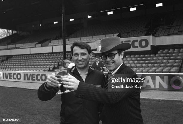 Watford FC manager Graham Taylor and Chairman Elton John share a drink on the Vicarage Road pitch in Watford, England on April 11, 1984.