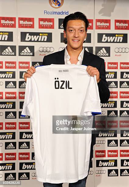 New signing Mesut Ozil poses with a Real Madrid shirt during his presentation as new Real Madrid player at the Estadio Santiago Bernabeu on August...