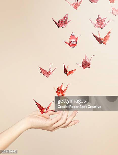 group of red origami cranes flying away from hand - oragami bildbanksfoton och bilder