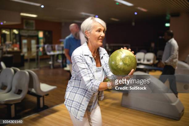 ältere frau in der kegelbahn - bowling stock-fotos und bilder