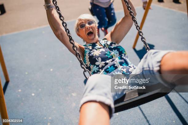 senior vrouw in de lucht op een schommel - adult stockfoto's en -beelden
