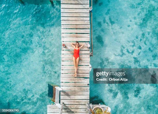 luchtfoto van womann ontspannen in een water-bungalow - beach lifestyle stockfoto's en -beelden