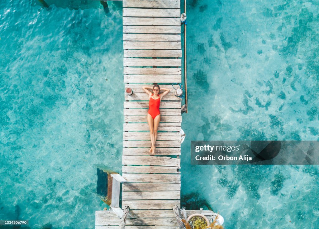 Aerial shot of womann relaxing in a water bungalow