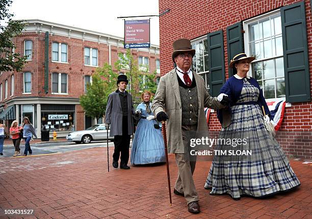 Reenactors dressed in Civil War period clothing walk through the town square to greet tourist on August 13, 2010 in Gettysburg Pennsylvania. The...