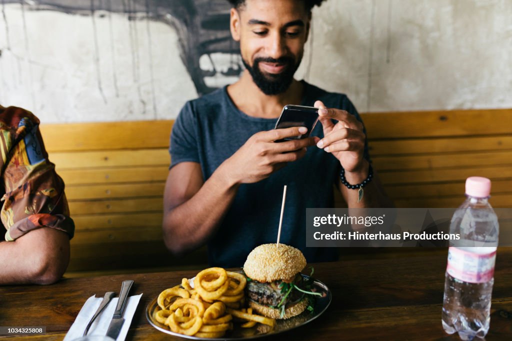 Man Taking Photos Of Burger With Smartphone
