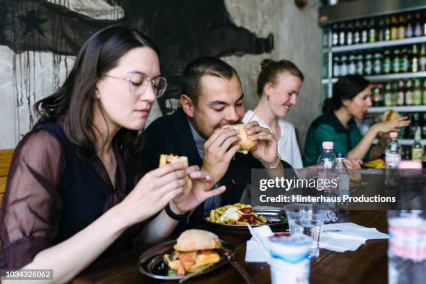 people enjoying food in burger restaurant - unhealthy living stock pictures, royalty-free photos & images