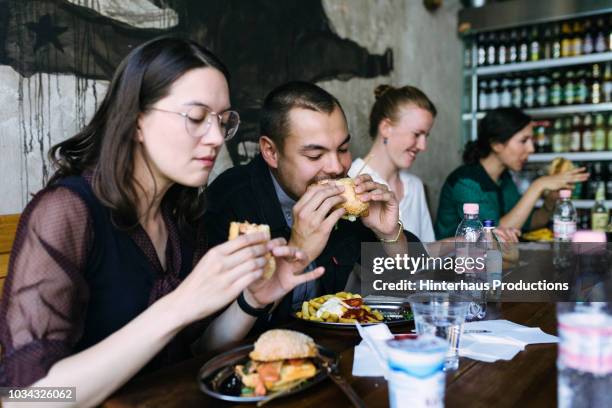 people enjoying food in burger restaurant - unhealthy living bildbanksfoton och bilder