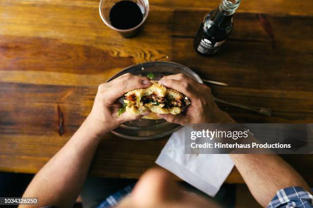 aerial view of man eating burger - food satisfaction stock pictures, royalty-free photos & images