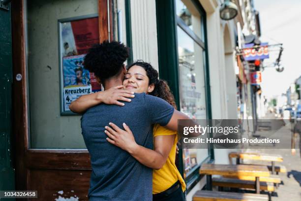 friends embracing outside restaurant - street restaurant stockfoto's en -beelden