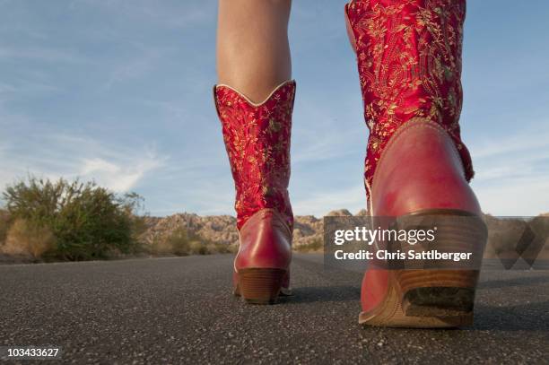 woman in red boots walking to horizon - cowboy boots stock pictures, royalty-free photos & images