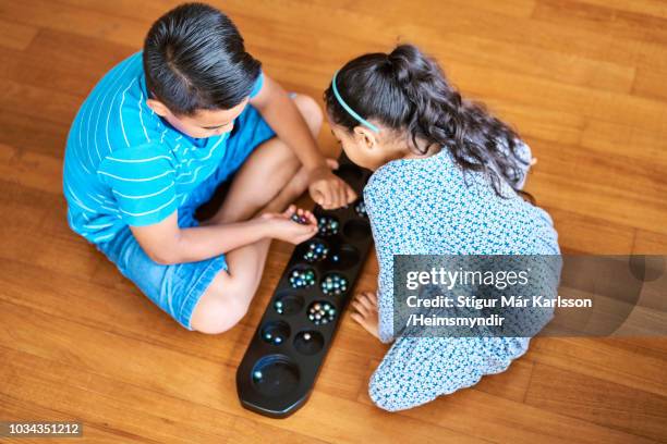 siblings playing wari board game at home - wari imagens e fotografias de stock