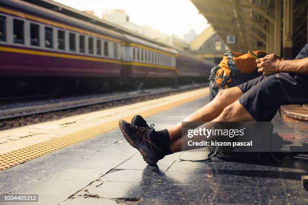 backpacker use phone in railway station while waiting train . . - rucksacktourist stock-fotos und bilder