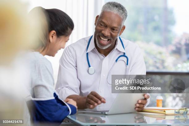 señor doctor hombre se ríe con el paciente - cabestrillo de brazo fotografías e imágenes de stock