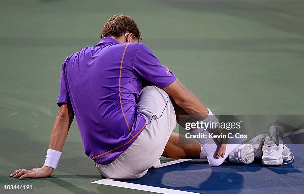 Denis Istomin of Uzebekistan sits down on the court after rolling his right ankle in his match against Roger Federer of Switzerland during Day 3 of...