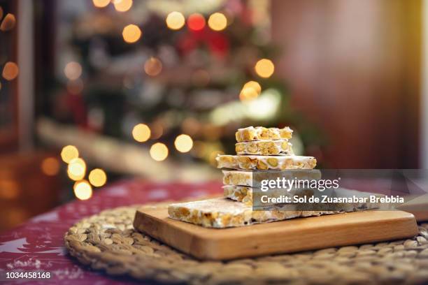 turrón, almond nougat, on wooden board next to the christmas tree - nougat stock pictures, royalty-free photos & images