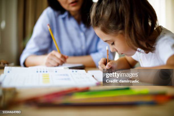 mutter hilft tochter bei den hausaufgaben - child at school learning stock-fotos und bilder