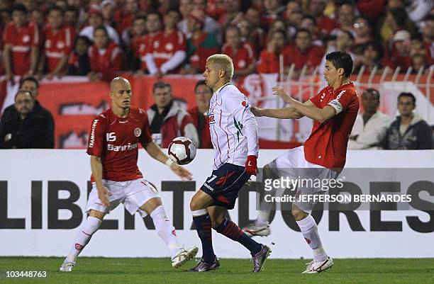 Adolfo Bautista of Mexico's Chivas vies for the ball with Nei and Bolivar of Brazilian Internacional during their Libertadores Cup final match at...