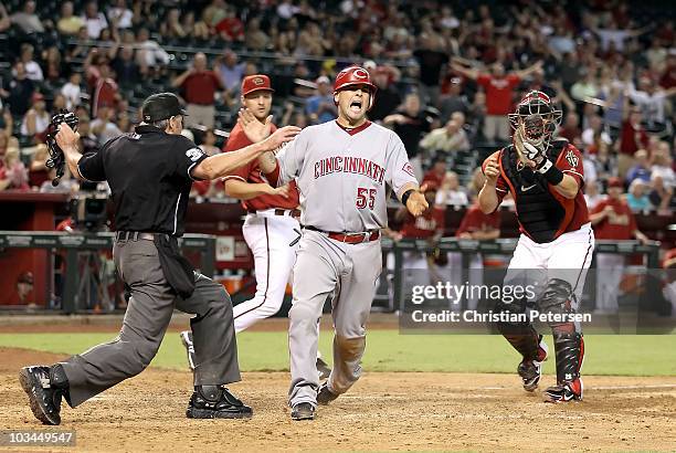 Ramon Hernandez of the Cincinnati Reds reacts after safely sliding in to score a run past catcher Miguel Montero of the Arizona Diamondbacks during...