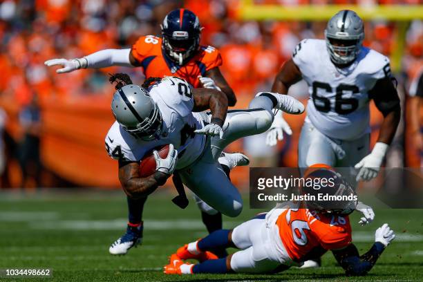 Running back Marshawn Lynch of the Oakland Raiders is hit by defensive back Darian Stewart of the Denver Broncos during the first quarter of a game...