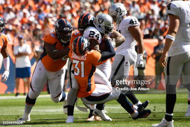 Justin Simmons of the Denver Broncos and others tackle Marshawn Lynch of the Oakland Raiders during the first quarter. The Denver Broncos hosted the...