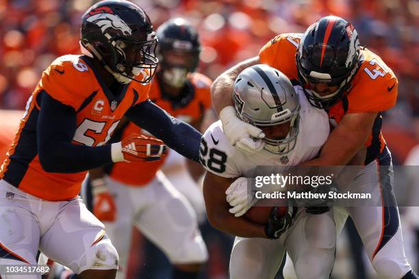 Running back Doug Martin of the Oakland Raiders is hit by linebacker Josey Jewell of the Denver Broncos during a game at Broncos Stadium at Mile High...